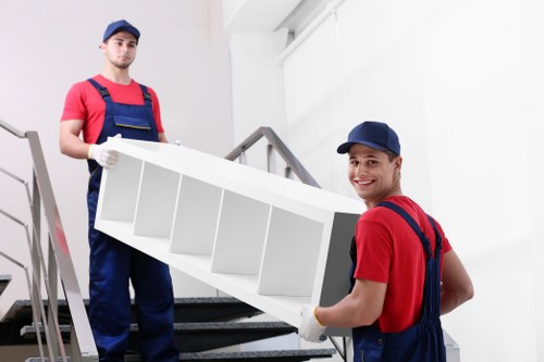 Specialist movers transporting a grand piano through a tight staircase in Shoreditch