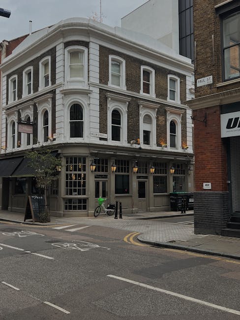 A three-storey Victorian-style building situated on a street corner in Shoreditch, featuring a white and brick facade with large sash windows and decorative trim. Adjacent to the building, there is a 